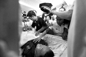 28日，兇手門多薩身著警服躺在棺木里。