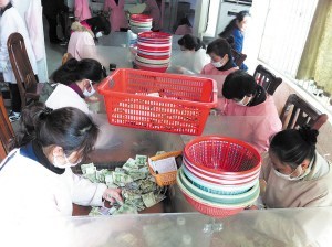 點鈔員們在低頭緊張地工作，她們每人每天都需要點鈔25箱1萬元以上。 陳暄 攝